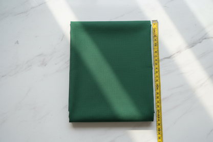 Flat lay of Dark Green Cotton Cambric Fabric with measuring tape showing 44 inch width