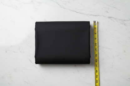 Flat lay of Black Cotton Poplin Lycra Fabric with measuring tape showing 44 inch width