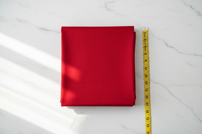 Flat lay of Candy Red Cotton Poplin Lycra Fabric with measuring tape showing 44 inch width