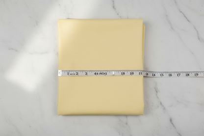 Flat lay of Lemon Cotton Poplin Fabric with measuring tape showing 44 inch width