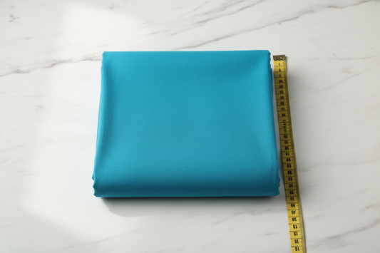 Flat lay of Blue Cotton Cambric Fabric with measuring tape showing 44 inch width