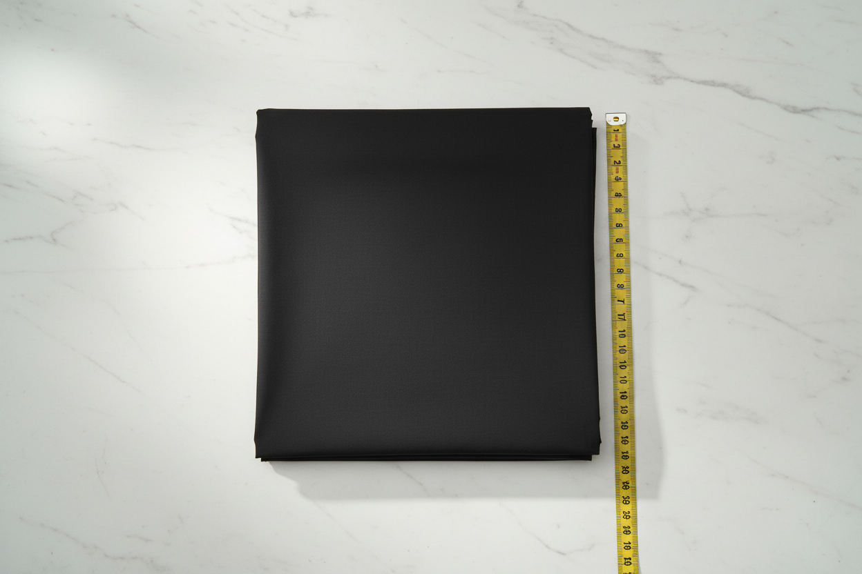 Flat lay of Black Cotton Cambric Fabric with measuring tape showing 44 inch width