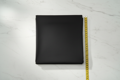 Flat lay of Black Cotton Cambric Fabric with measuring tape showing 44 inch width