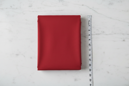 Flat lay of Red Cotton Cambric Fabric with measuring tape showing 44 inch width